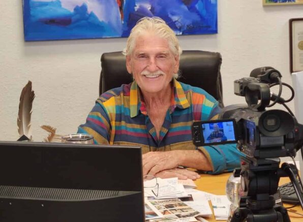 Robert Morse, N.D., D.Sc., M.H. in colorful shirt preparing for recording session with camera and microphone setup.